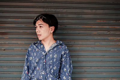 Young man standing against shutter