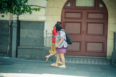 Rear view of woman standing against building