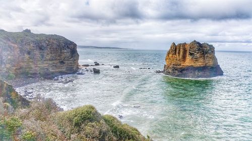 Rock formation in sea against sky