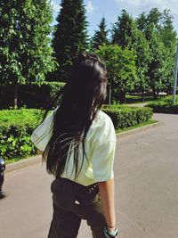 Rear view of woman walking on road amidst trees