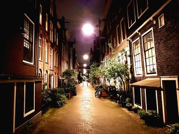 Illuminated street amidst buildings in city at night