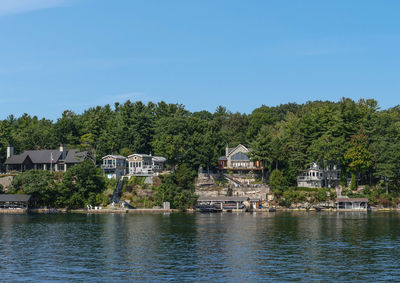 Houses by river and buildings against sky