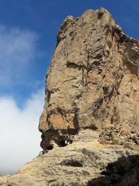 Low angle view of person on cliff against sky