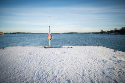 Snow covered on pier at lake against sky