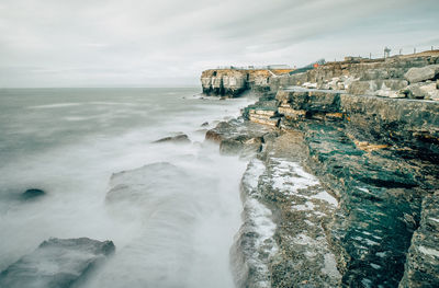 Aerial view of rocky coastline against sky