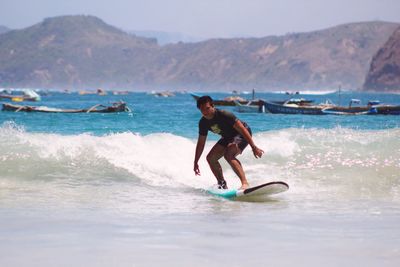 Portrait of young man surfing on sea against sky