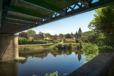 Arch bridge over river by buildings against sky