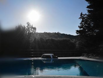 Swimming pool by lake against sky