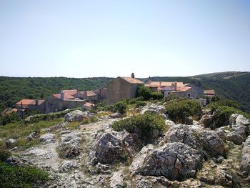 Houses by buildings against clear sky