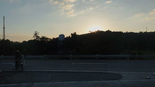 Silhouette woman by railing against sky during sunset