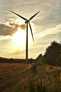 Low angle view of windmill on field against sky during sunset