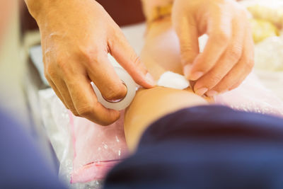 Cropped hands of doctor applying bandage to patient at hospital