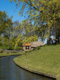 House by lake and trees against sky