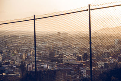 View of city seen through chainlink fence