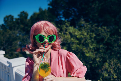 Young woman wearing sunglasses while standing against trees