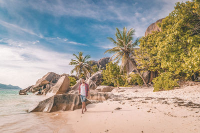 Mid adult man walking at beach against blue sky