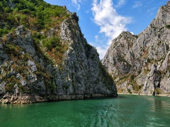 Scenic view of sea by mountain against sky
