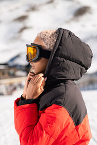 A african american woman wearing goggles standing in snowy mountain during winter	