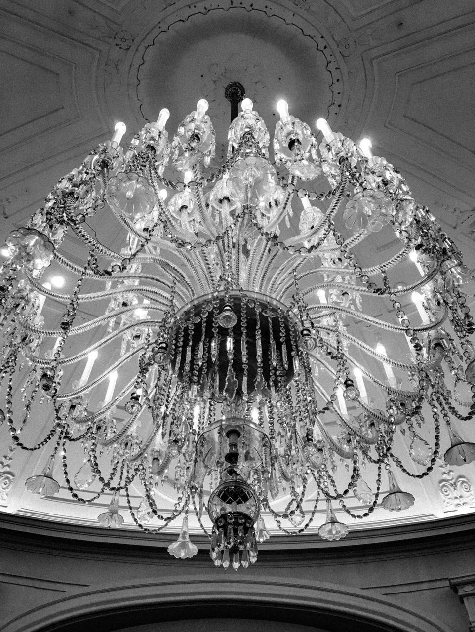 LOW ANGLE VIEW OF ILLUMINATED CHANDELIER HANGING FROM CEILING