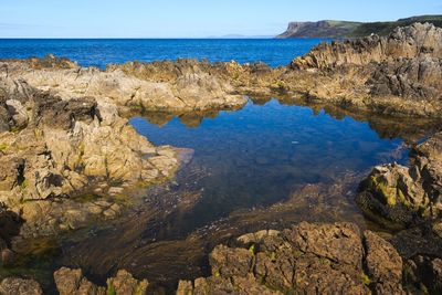 Scenic view of sea by cliff against sky