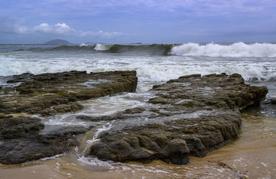 Scenic view of rocks on beach against sky