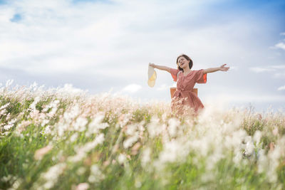 A young asian girl on a beautiful spring meadow. she wears a pink dress and wide-brimmed hat.