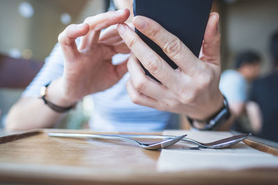 Midsection of person using mobile phone at table