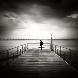 Pier on sea against cloudy sky