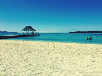 Scenic view of beach against clear blue sky