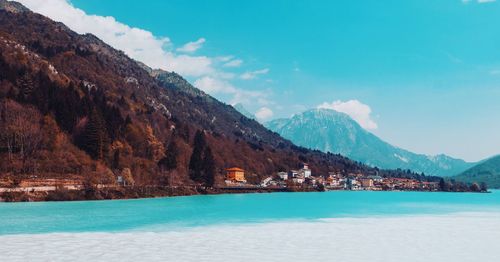 Scenic view of sea by mountains against sky