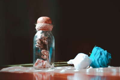 Close-up of glass jar on table against black background