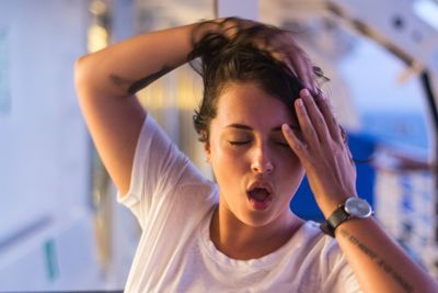 Close-up of young woman with eyes closed yawning