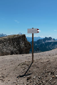 Sign board on mountain against blue sky