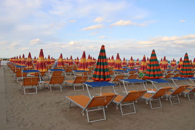 Empty chairs on beach against sky