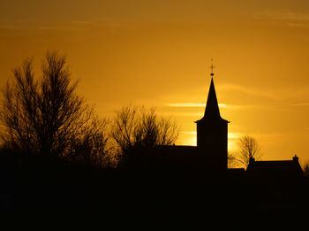 Silhouette trees and building against sky during sunset