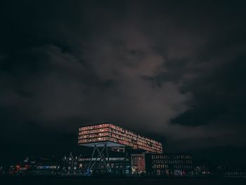 Illuminated building against cloudy sky at night