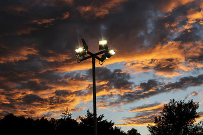 Low angle view of silhouette street light against orange sky
