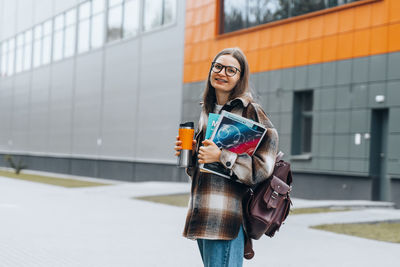 Young woman standing against wall in city