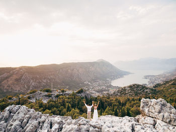 Man standing on rocks by mountains against sky