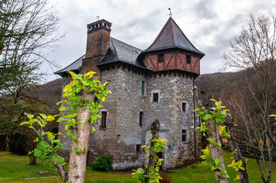 Old building by trees against sky