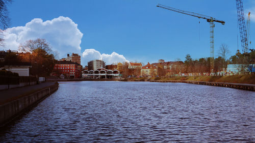 Buildings by river against sky in city