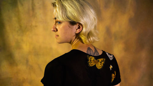 Side view of young man standing against wall