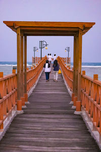 Rear view of people on pier amidst sea against sky