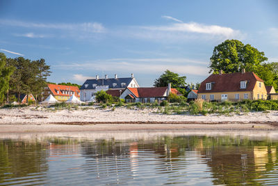 Houses by river and buildings against sky