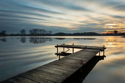 Fantastic cloud bands on the sky and a wooden fishing pier, february cool evening