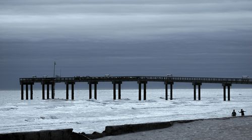 Wooden pier on sea against cloudy sky