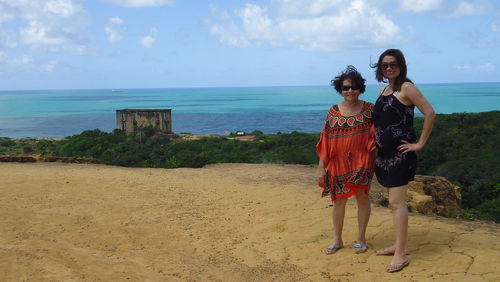 Woman with mother standing at forte castelo do mar against sea and sky on sunny day