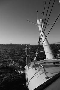 Sailboats moored in sea against clear sky