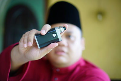 Portrait of man showing electronic cigarette