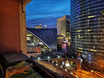 Illuminated buildings in city against sky at dusk